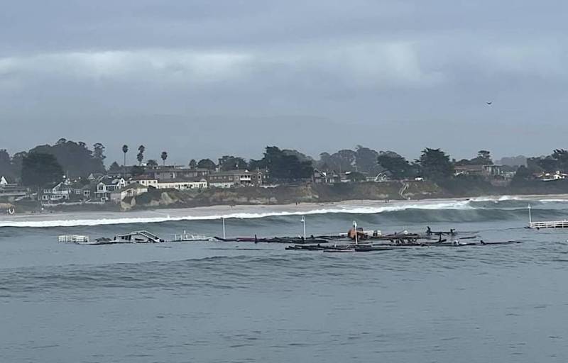 A broken pier floating in the water, with big waves.