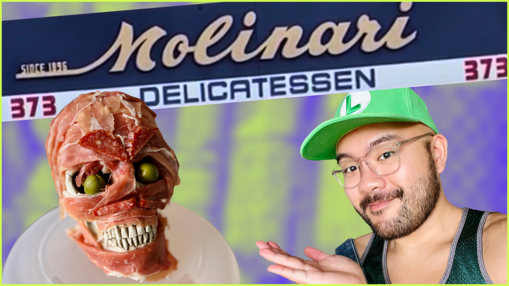 Young bearded Filipino man wears a green Super Mario Brothers hat. On the left is a plastic skull covered in deli meat slices. Molinari Delicatessen sign in the background.